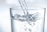 Close up pouring water into glass on a blue background