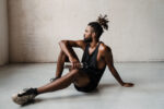 Image of african american sportsman sitting on floor with water bottle