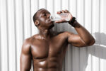 Portrait of a young thirsty african sportsman drinking water