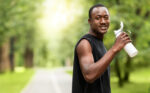 Positive african runner having break, drinking water