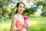 Sport woman drinking water in park