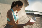 Young tired fitness woman sitting and holding water bottle